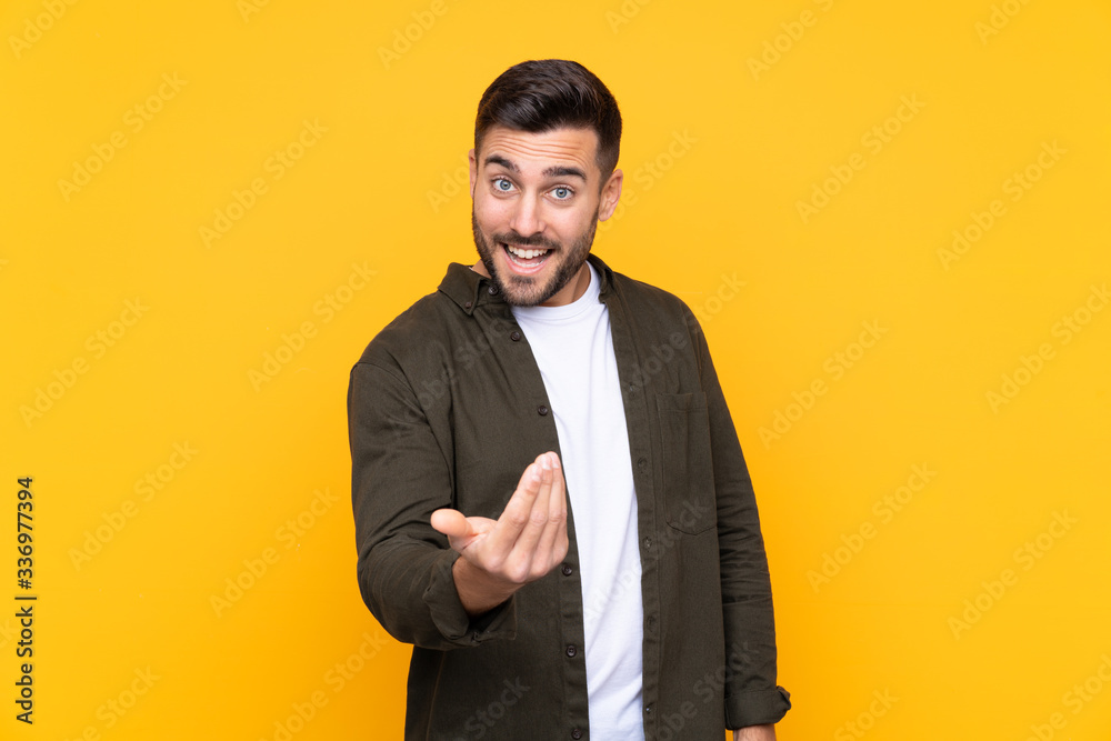 Man over isolated yellow background inviting to come Man over isolated yellow background inviting to come
