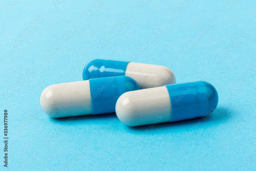 Pills isolated on blue background. Medical drug capsule. Concept of coronavirus Pills isolated on blue background. Medical drug capsule. Concept of coronavirus