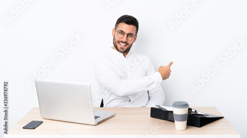 Young businessman in a workplace pointing back