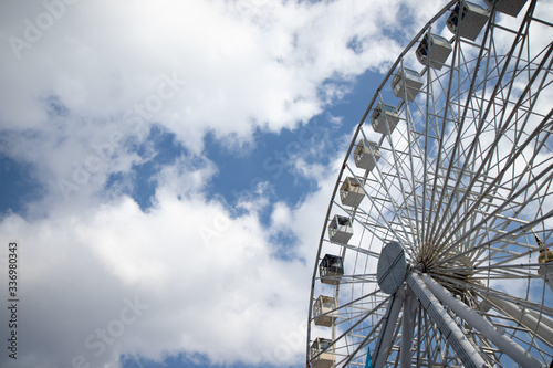 Ferris wheel in an amusement park against a on white and blue sky