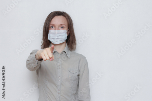 Woman in protective medical mask choosing you, pointing finger at camera. Coronavirus, pandemic, safety, protection, warning, caution © Евгения Савина
