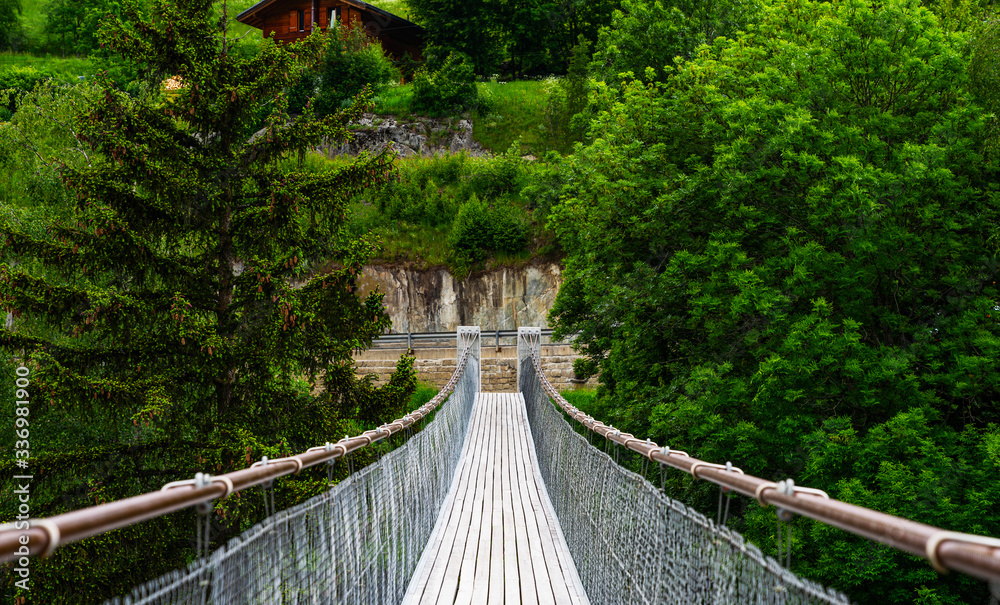 Obraz premium View of suspension bridge in Swiss Alps. Suspension bridge, crossing the river, crossing in the woods.