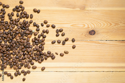 Roasted coffee beans randomly dumped on a wooden table