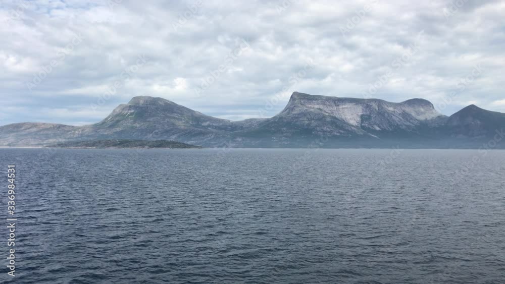 A Norwegian coast or fjord cloudy day seen by the sea near Lofoten islands in Norway. A Norwegian coast or fjord cloudy day seen by the sea near Lofoten islands in Norway.