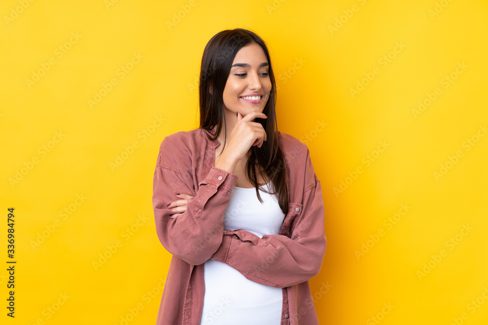 Young brunette woman over isolated yellow background looking to the side Young brunette woman over isolated yellow background looking to the side