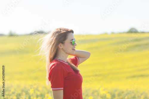 Happy young woman in a red dress in the rape field
