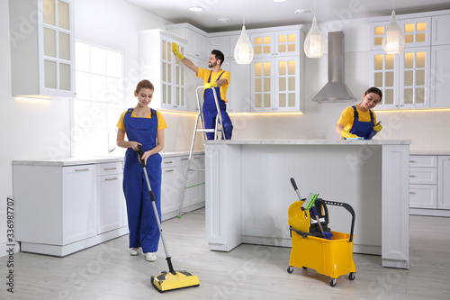 Team of professional janitors cleaning modern kitchen