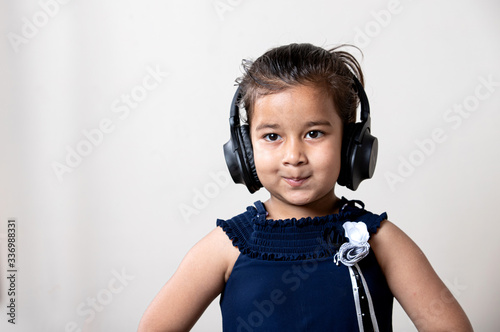 Cute little girl with headphones listening music  giving cute expression  photo