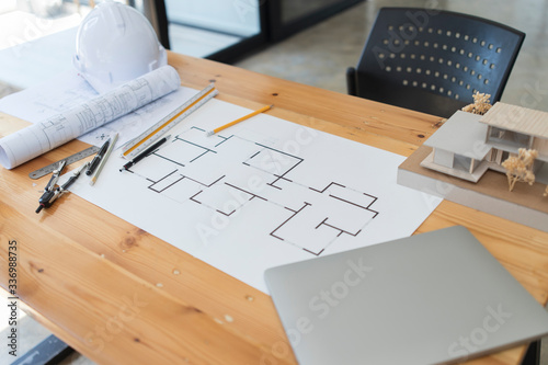 Architectural plan, laptop, dividers ,pencil ,pen ,ruler, glasses and smartphone and blueprint on wooden table. Architectural blueprints office desk background construction project ideas concept.