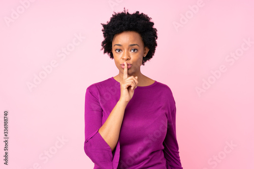 African american woman over isolated pink background showing a sign of silence gesture putting finger in mouth
