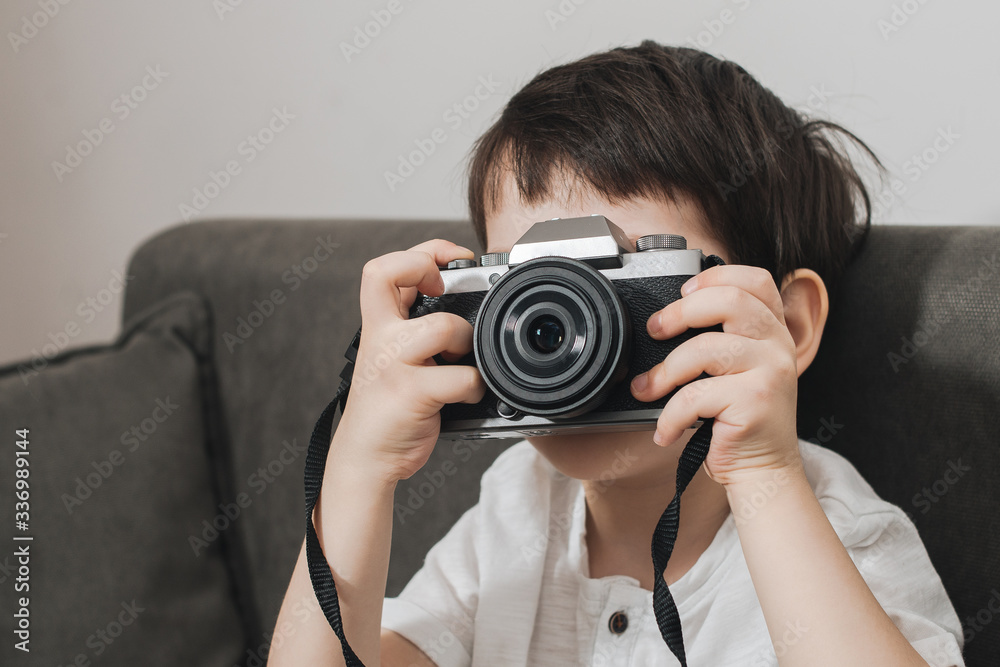 Beautiful smiling child (kid, boy) - photographer holding a instant camera intdoors Beautiful smiling child (kid, boy) - photographer holding a instant camera intdoors