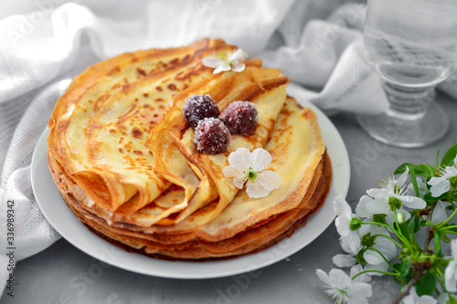 Thin homemade pancakes. Light background. Beautiful and delicious breakfast at home or in the cafe. Thin aromatic pancakes with cherries and berries. Side view. Light napkin.