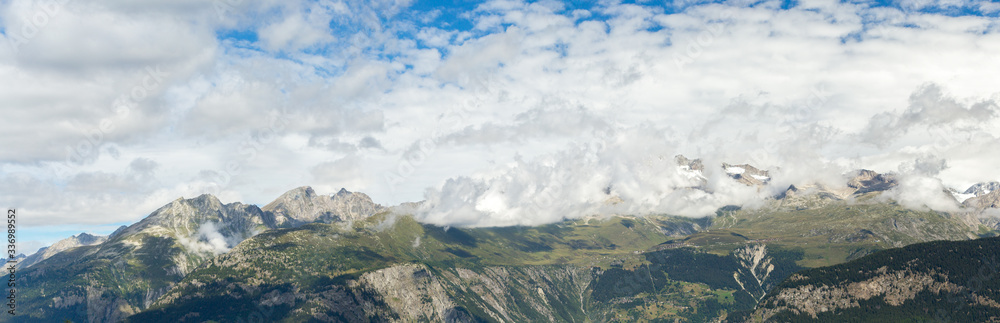 ridges of Swiss mountains panorama in summer, cloudy weather