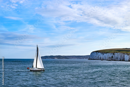 Sailing Yacht sailing in the English Channel off the white cliffs in calm water with blue sky and some cloud. photo