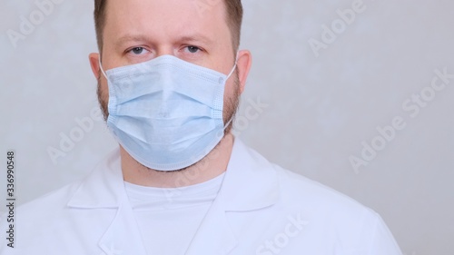 Male in a protective mask and a white shirt looks at the camera  close-up. Hygiene concept. prevent the spread of germs and bacteria and avoid infection with the crown virus. copy space
