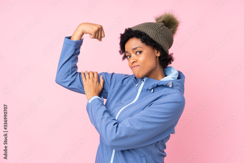 African american woman with winter hat over isolated pink background making strong gesture African american woman with winter hat over isolated pink background making strong gesture