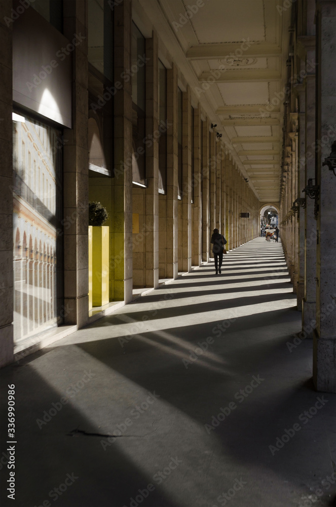 Corridor made up of lights and shadows from the architectural columns that make it up while a person walks through it
