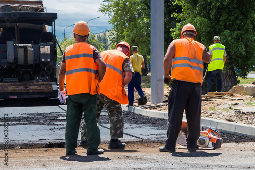 asphalt laying, workers in overalls