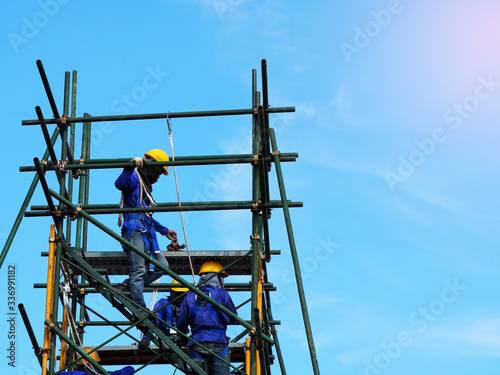 Construction workers working on scaffolding,Man Working on the Working at height with blue sky at construction site