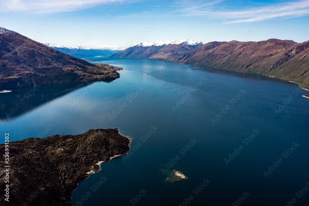 Stunning aerial image of the Wanaka lake with the snowy Mount Aspiring in the background on a sunny winter day, New Zealand