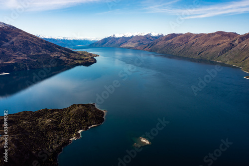 Stunning aerial image of the Wanaka lake with the snowy Mount Aspiring in the background on a sunny winter day, New Zealand