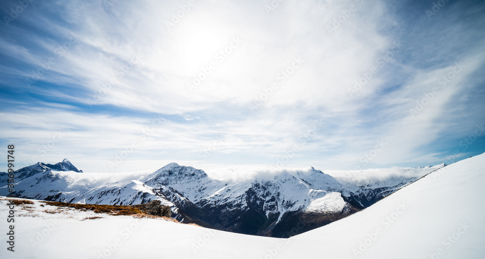 Beautiful panorama of the snow capped mountains with the snowy Mount Aspiring in the background taken on a sunny winter day in Wanaka, New Zealand