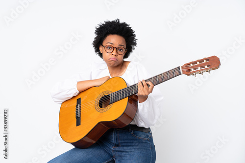 African american woman with guitar over isolated background making doubts gesture while lifting the shoulders