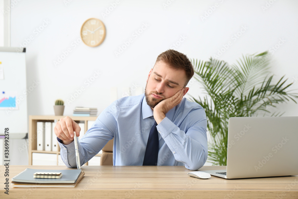 Lazy young office employee procrastinating at workplace - obrazy, fototapety, plakaty 