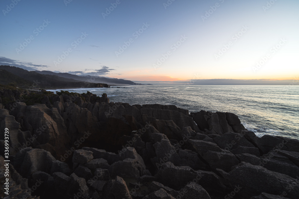 Beautiful panorama of an orange sunset at Pancake Rocks on a sunny winter day in Punakaiki, New Zealand