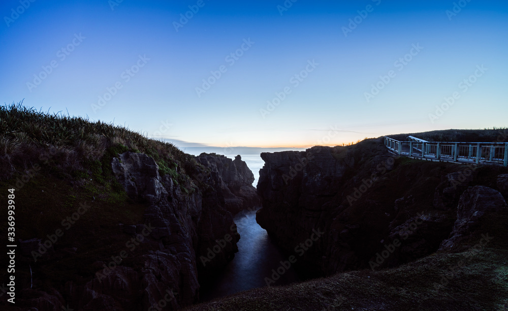 Fototapeta premium Beautiful panorama of an orange sunset at Pancake Rocks on a sunny winter day in Punakaiki, New Zealand