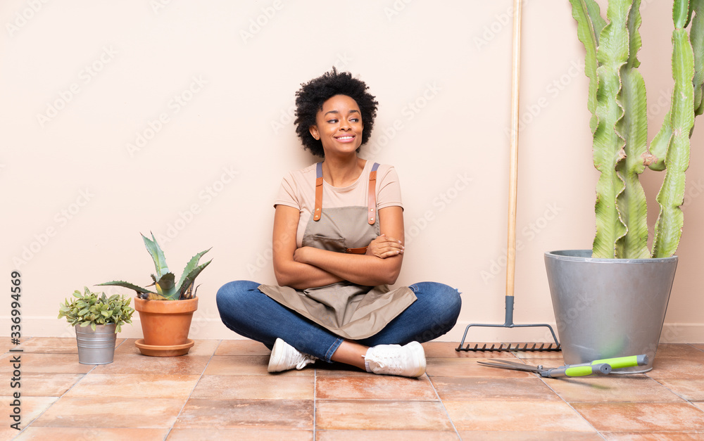 Gardener woman sitting on the floor with arms crossed and happy Gardener woman sitting on the floor with arms crossed and happy