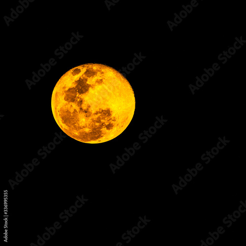 Gros plan d'une super pleine lune jaune orangée au-dessus la Guadeloupe en début de soirée dans un ciel totalement dégagé