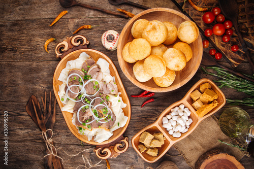 Top view on a traditional national kazakh cuisine dishes Beshbarmak with boiled dough and meat in wooden bowl, baursaks fried dough on a wooden table horizontal