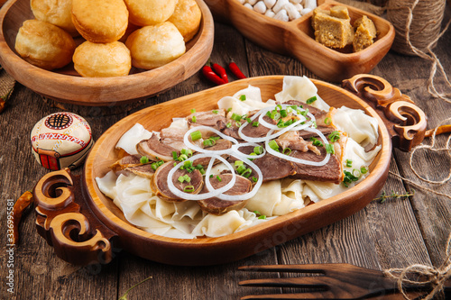Traditional national kazakh cuisine dish Beshbarmak with boiled dough and meat in wooden bowl, horizontal