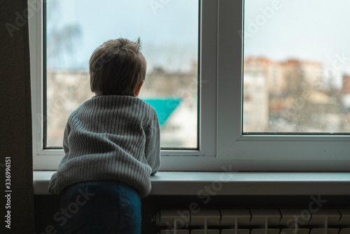 Little boy looks out the window and wants to go outside