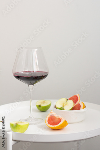 glass of red wine and fruits on the kitchen table 