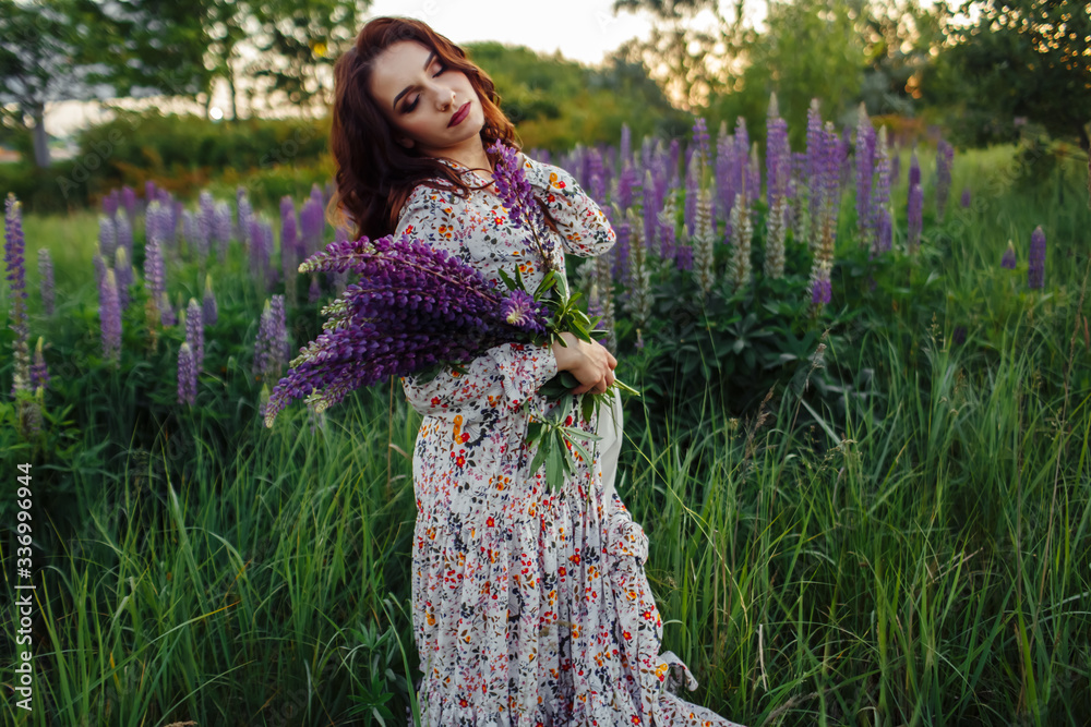brunette in a flower field.The girl holds lupines purple. brunette in a flower field.The girl holds lupines purple.