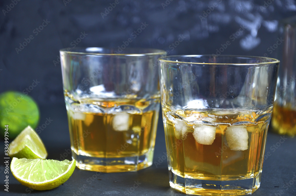 Drink cold tea with ice cubes and mint in two glass goblets a dark black background. Alcoholic or non-alcoholic mahito. whiskey or scotch tape, with lime or lemon Drink cold tea with ice cubes and mint in two glass goblets a dark black background. Alcoholic or non-alcoholic mahito. whiskey or scotch tape, with lime or lemon