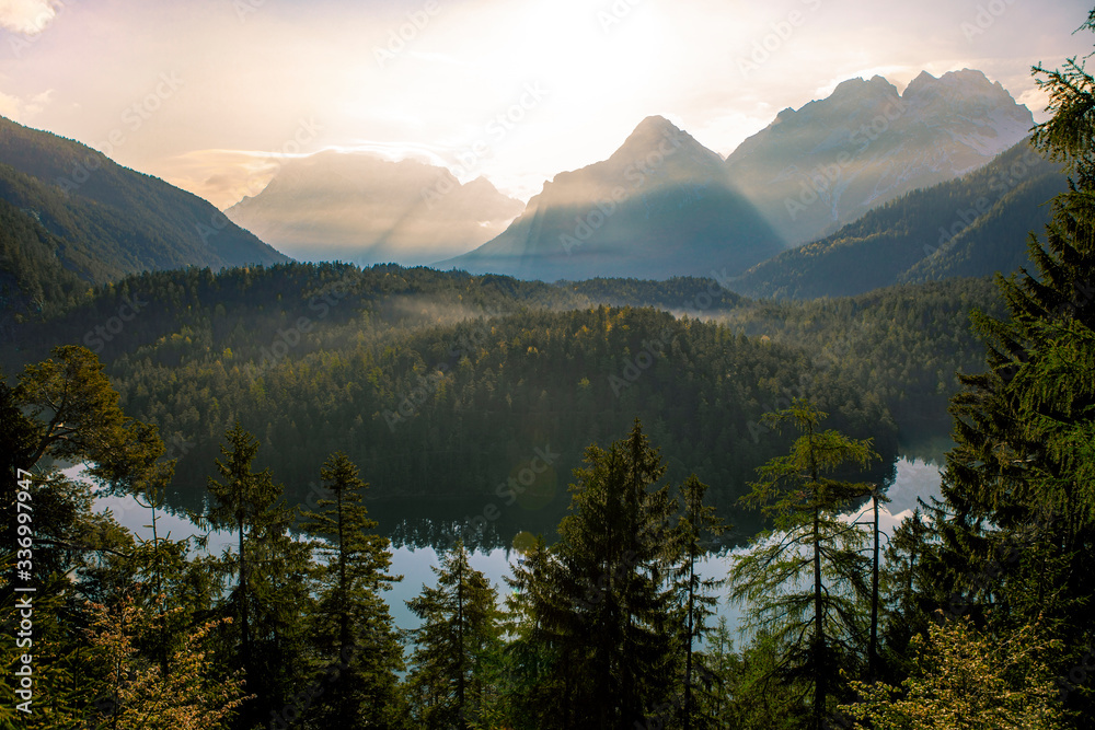 Blindsee in Tyrol, Austria during sunrise with lightbeams and mountains in the background
