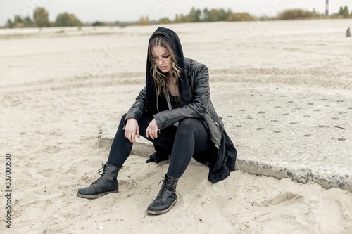 young woman with scarred face and urban black clothes posing