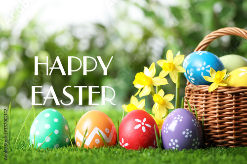 Colorful eggs with daffodil flowers and text Happy Easter on blurred background