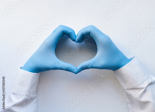 Hands of a doctor or nurse in medical gloves depict a heart on a white background, caring doctor and medicine concept.
