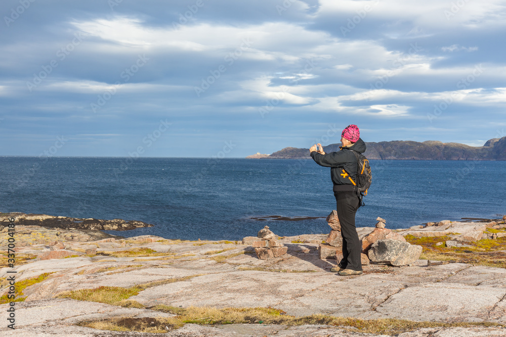 A middle-aged woman photographs the Barents Sea., travel concept