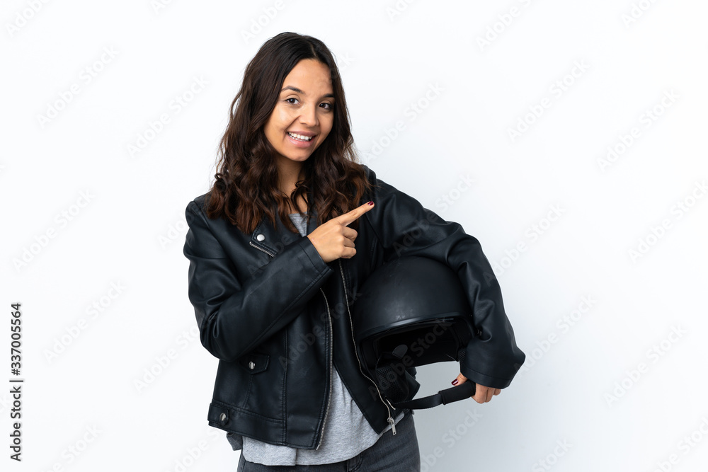 Young woman holding a motorcycle helmet over isolated white background pointing to the side to present a product Young woman holding a motorcycle helmet over isolated white background pointing to the side to present a product