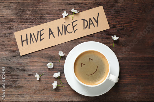 Fototapeta Delicious coffee, flowers and card with HAVE A NICE DAY wish on wooden table, flat lay