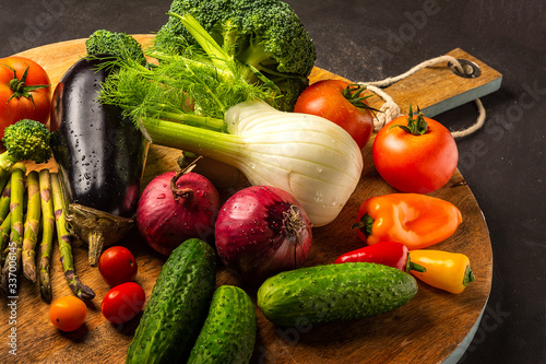 Exposition of fresh organic vegetables on wooden plate. tomato, pepper, broccoli, onion, garlic, cucumber,  eggplant, black Eyed Peas, ecological bag.