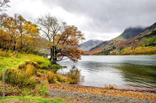 The east side of Lake Buttermere with Haystacks in the distance covered by clouds in the Lake District. 