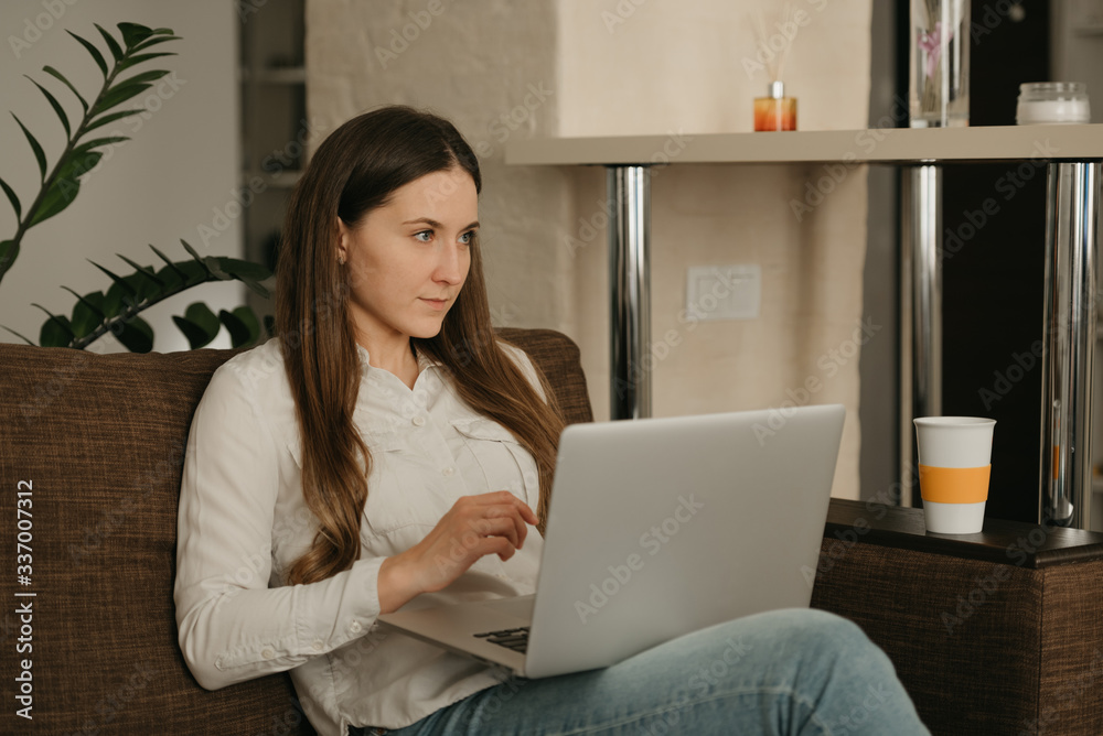 Remote work. A caucasian woman working remotely on her laptop. A girl doing business from home on the sofa. Remote work. A caucasian woman working remotely on her laptop. A girl doing business from home on the sofa.
