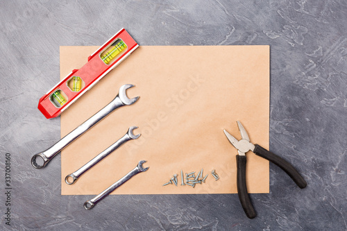 Photos Different hand tools for construction, repair- pliers, level tool, screw, spanner on craft envelope with free space on grey background