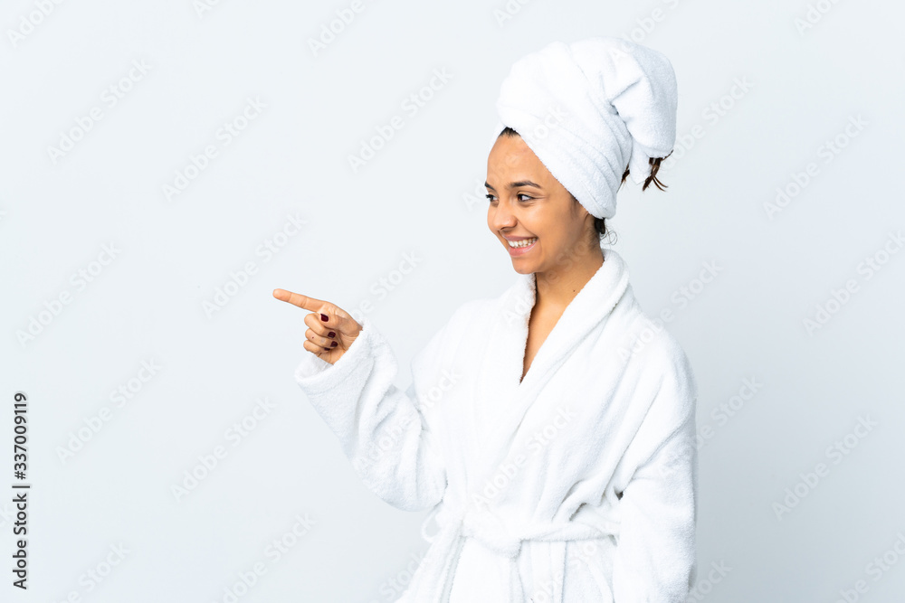 Young woman in bathrobe over isolated white background pointing finger to the side and presenting a product Young woman in bathrobe over isolated white background pointing finger to the side and presenting a product